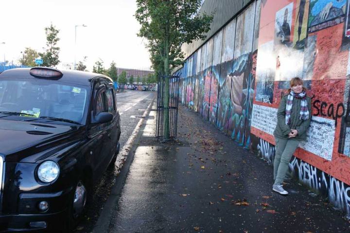 A woman posing by the peace wall in Belfast Ireland